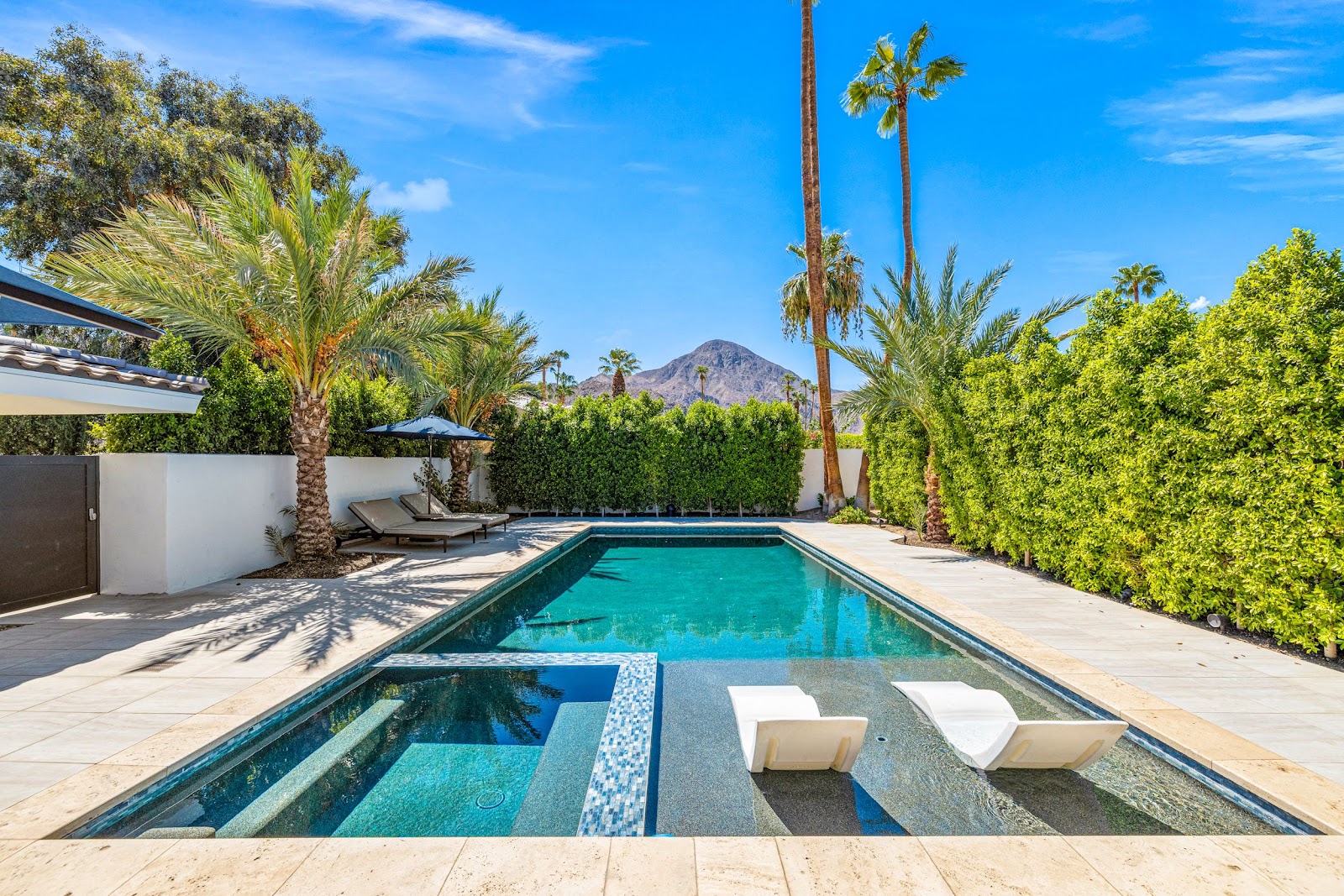 A pool home in Indian Wells, California, with palm trees and desert mountains in the distance