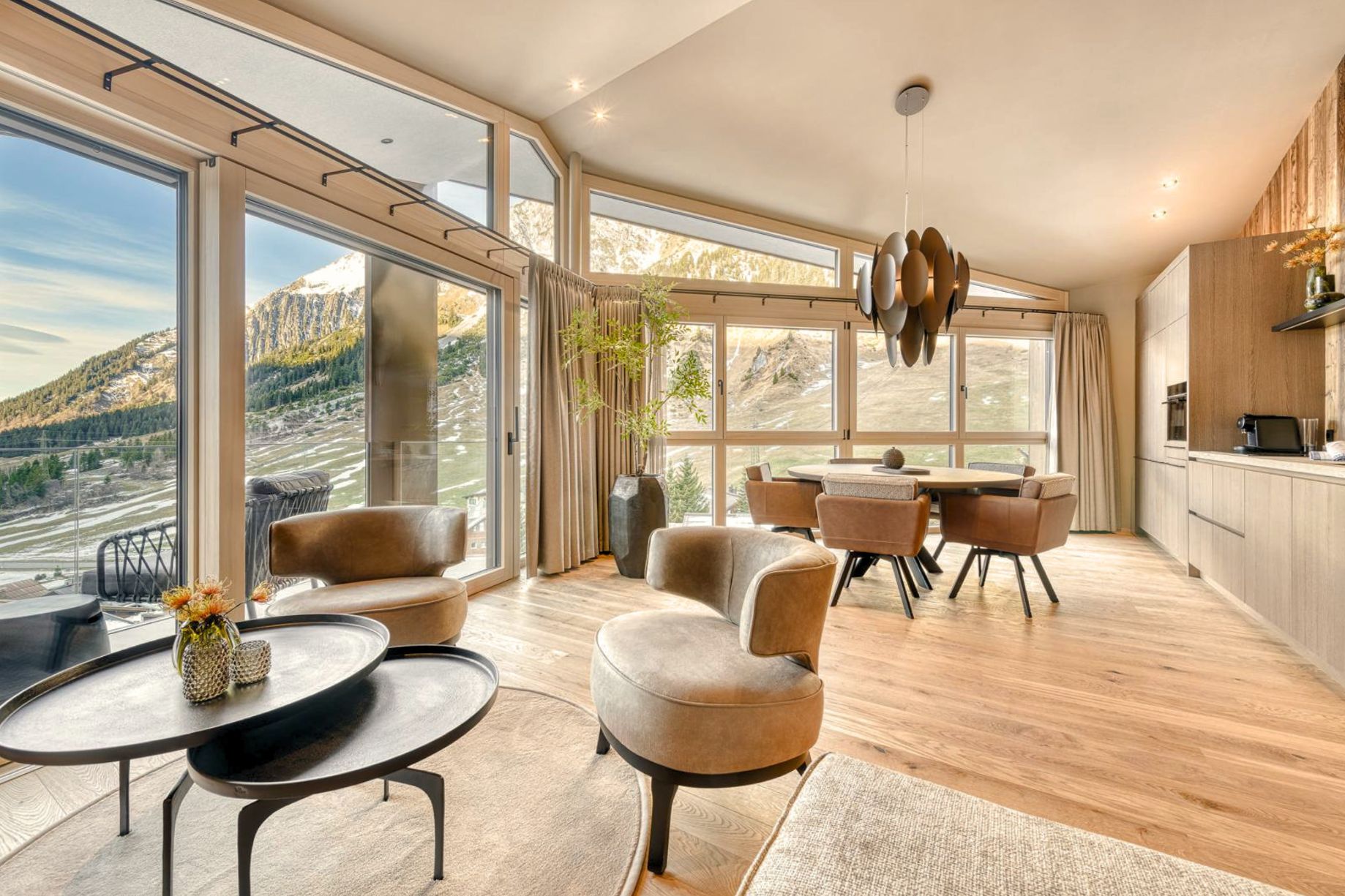 Open-plan living and dining room in the Stuben penthouse, with floor-to-ceiling windows facing the mountains.