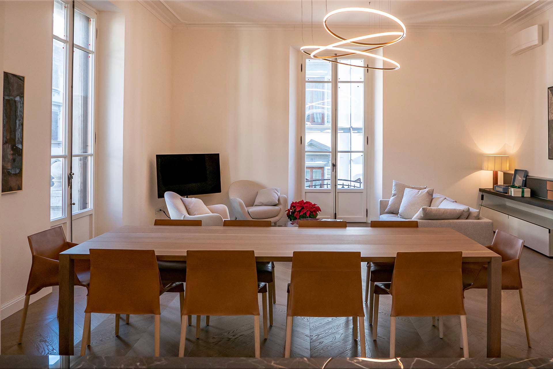 A bright Florentine apartment interior with herringbone parquet, tall windows and a long dining table